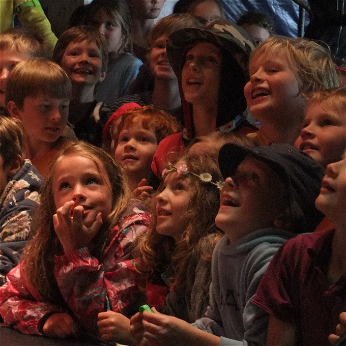 Happy children facing the stage enjoying a comedy performance