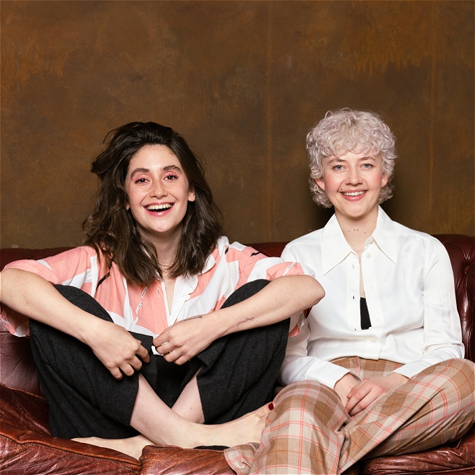 Charly Clive and Ellen Robertson of Britney sit smiling on a old sofa.